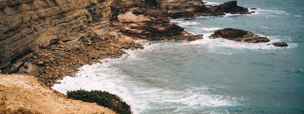 Aerial view of ocean crashing on the rocks in Faro District, Portugal