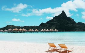 Charming tropical island with cottages and beach chairs in French Polynesia