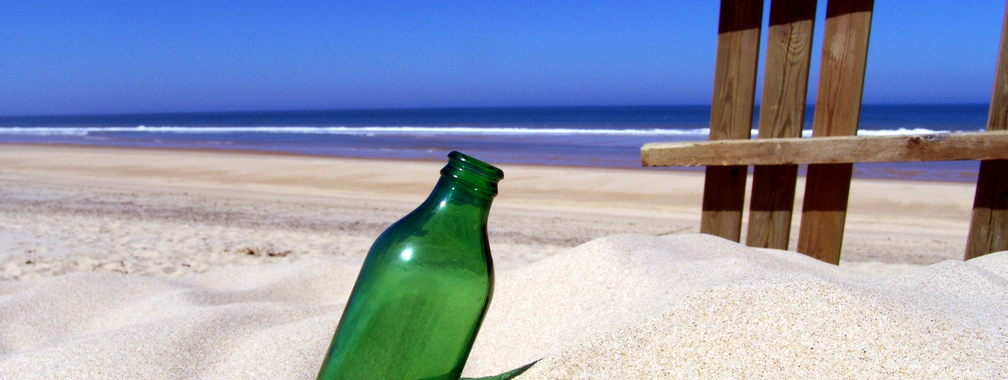 Green bottle on sandy beach wallpaper