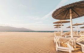 Lounge chairs with umbrellas at the beach during day at Crete Region, Greece