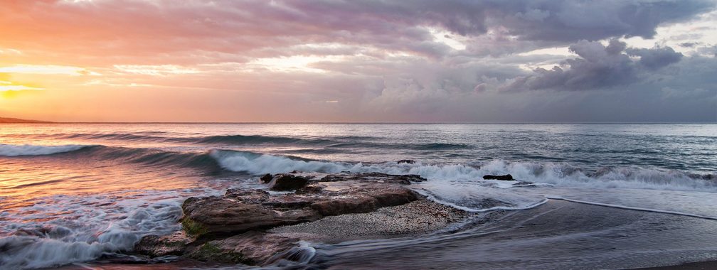 Stormy orange beach sunrise at Playa de la Misericordia, Spain