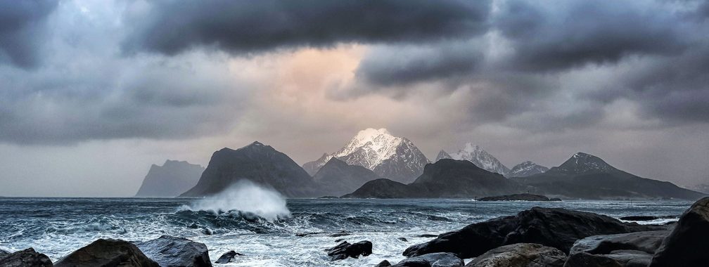 Waves crashing on rocks near mountains in Myrland, Norway