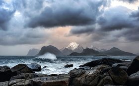 Waves crashing on rocks near mountains in Myrland, Norway